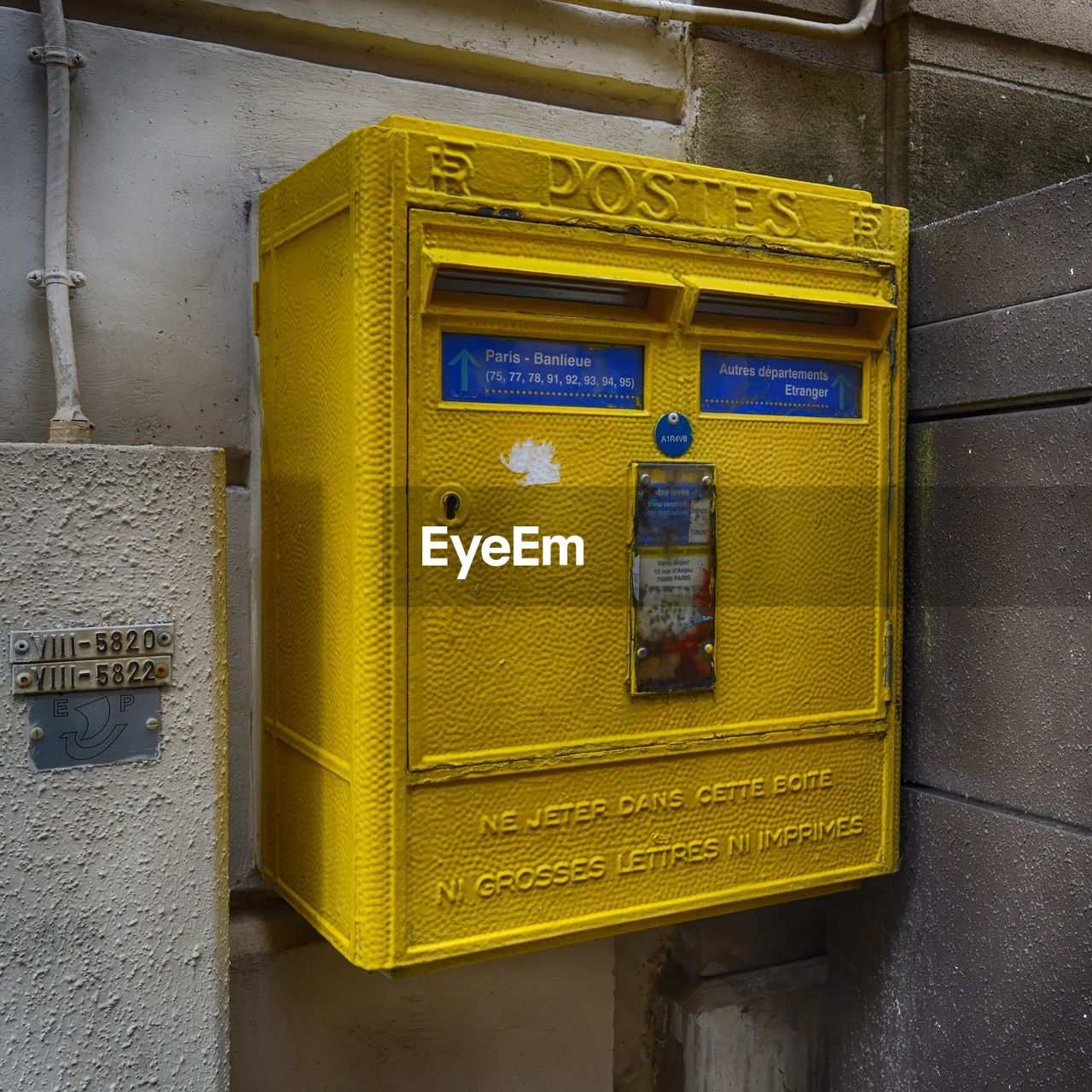 CLOSE-UP OF YELLOW MAILBOX ON METAL