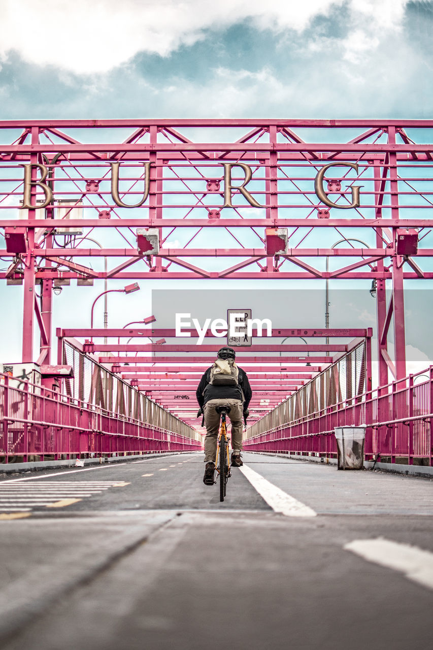 FULL LENGTH REAR VIEW OF MAN RIDING BICYCLE ON BRIDGE