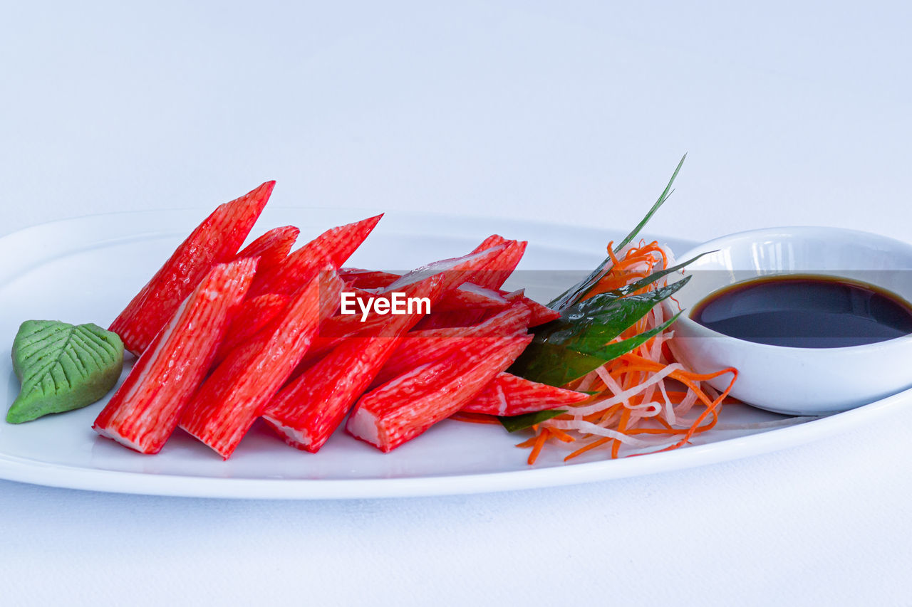 CLOSE-UP OF RED CHILI PEPPERS IN PLATE AGAINST WHITE BACKGROUND