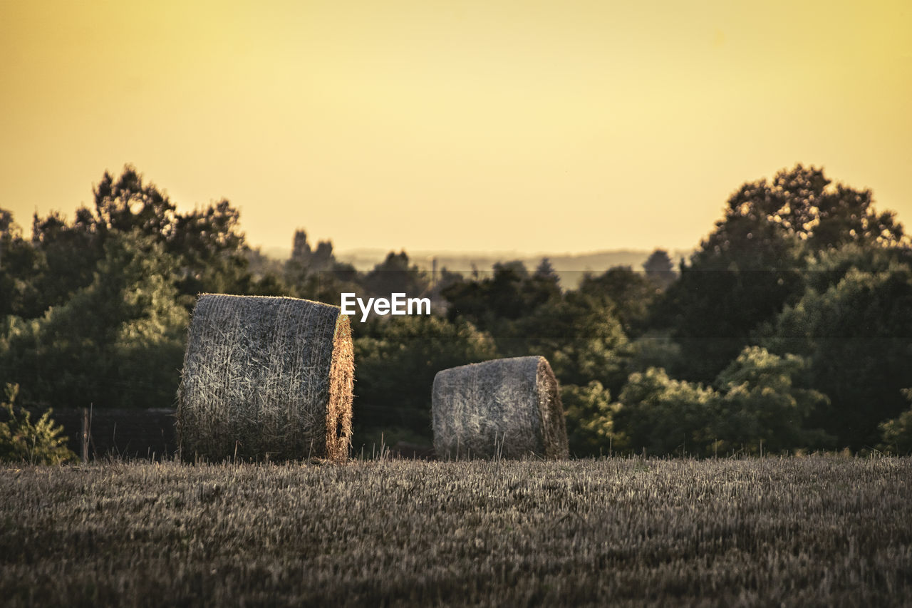 Hay bales on field against sky during sunset