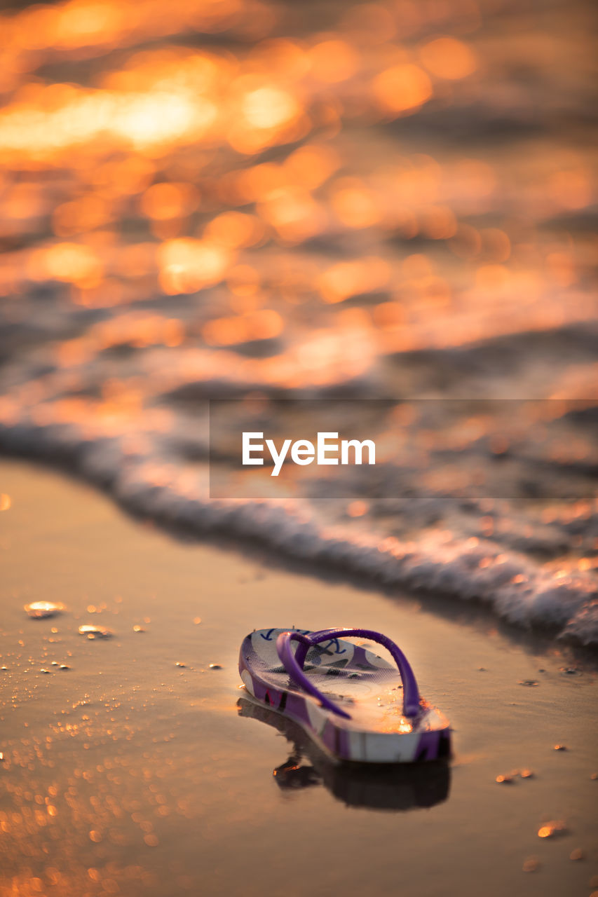 Photo of a flip flop at the beach at sunset 