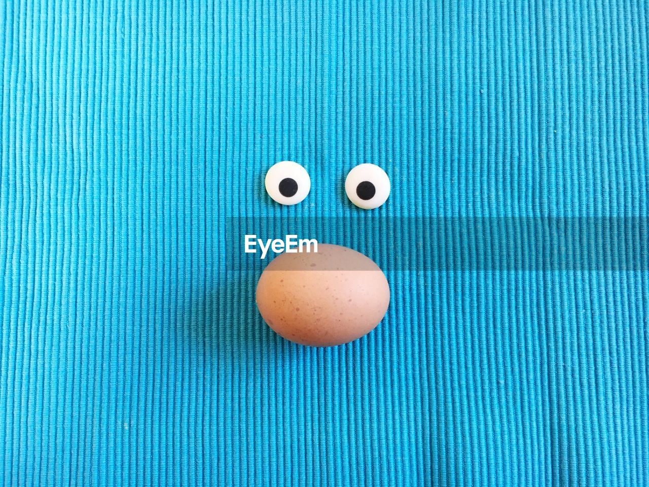 Directly above shot of googly eyes and egg on fabric during easter