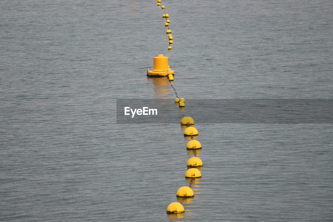 High angle view of line of yellow buoys  in sea.