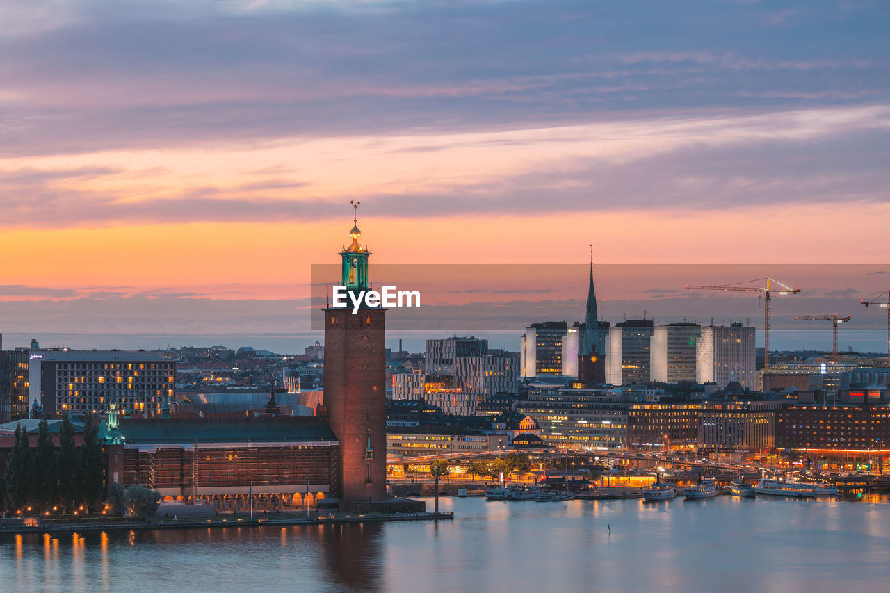 illuminated buildings in city at sunset