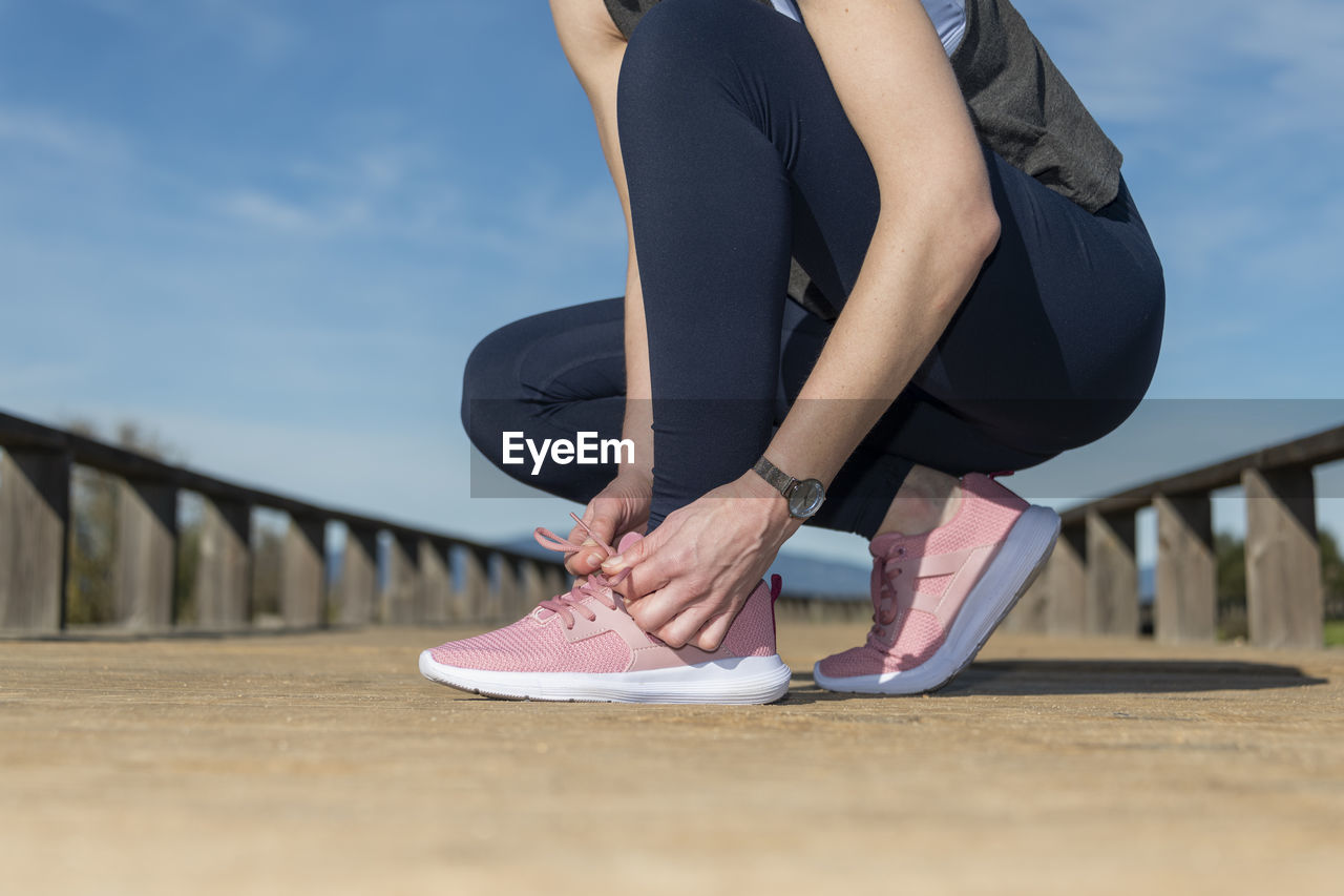 Female tying up laces on running shoes, preperation before jogging.