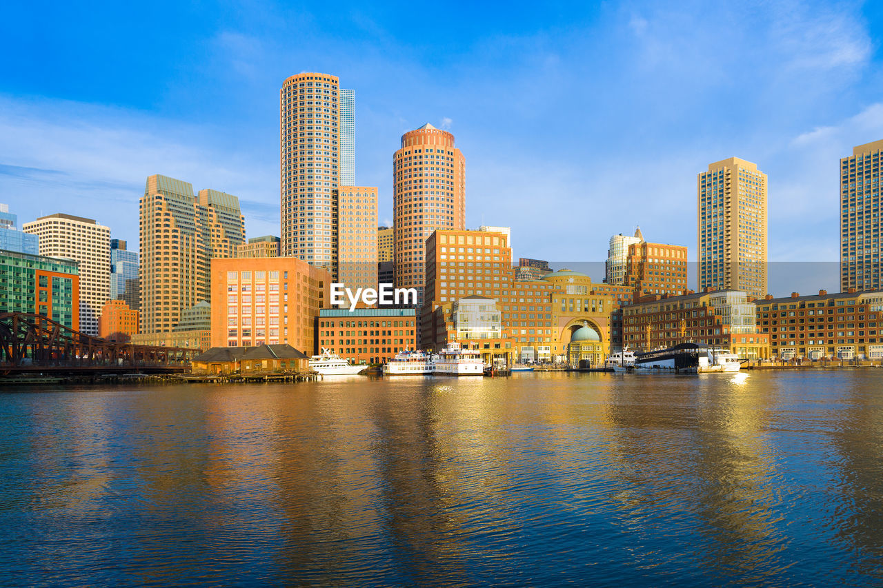 Illuminated buildings by river against sky in city