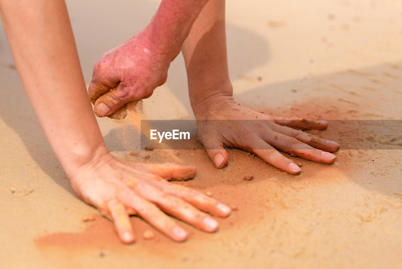 Cropped image of hands playing with sand at beach