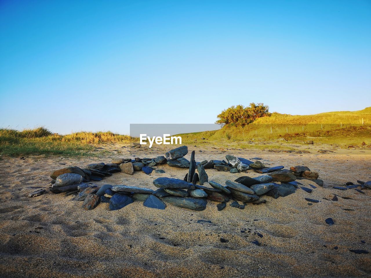 Scenic view of land against clear blue sky with a circle of stones