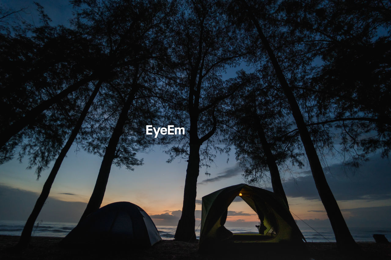 Silhouette camping tent on beach with sunrise and sea background