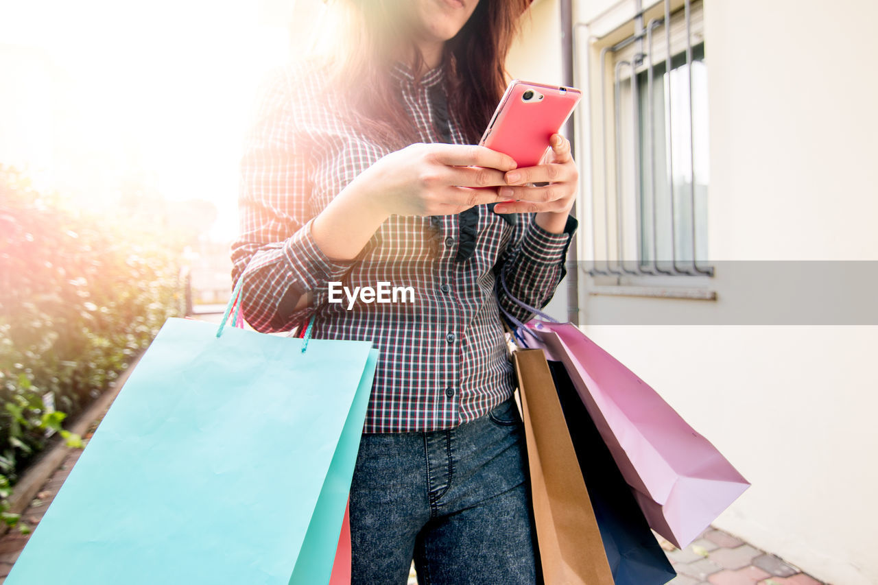 Young woman with shopping using mobile phone