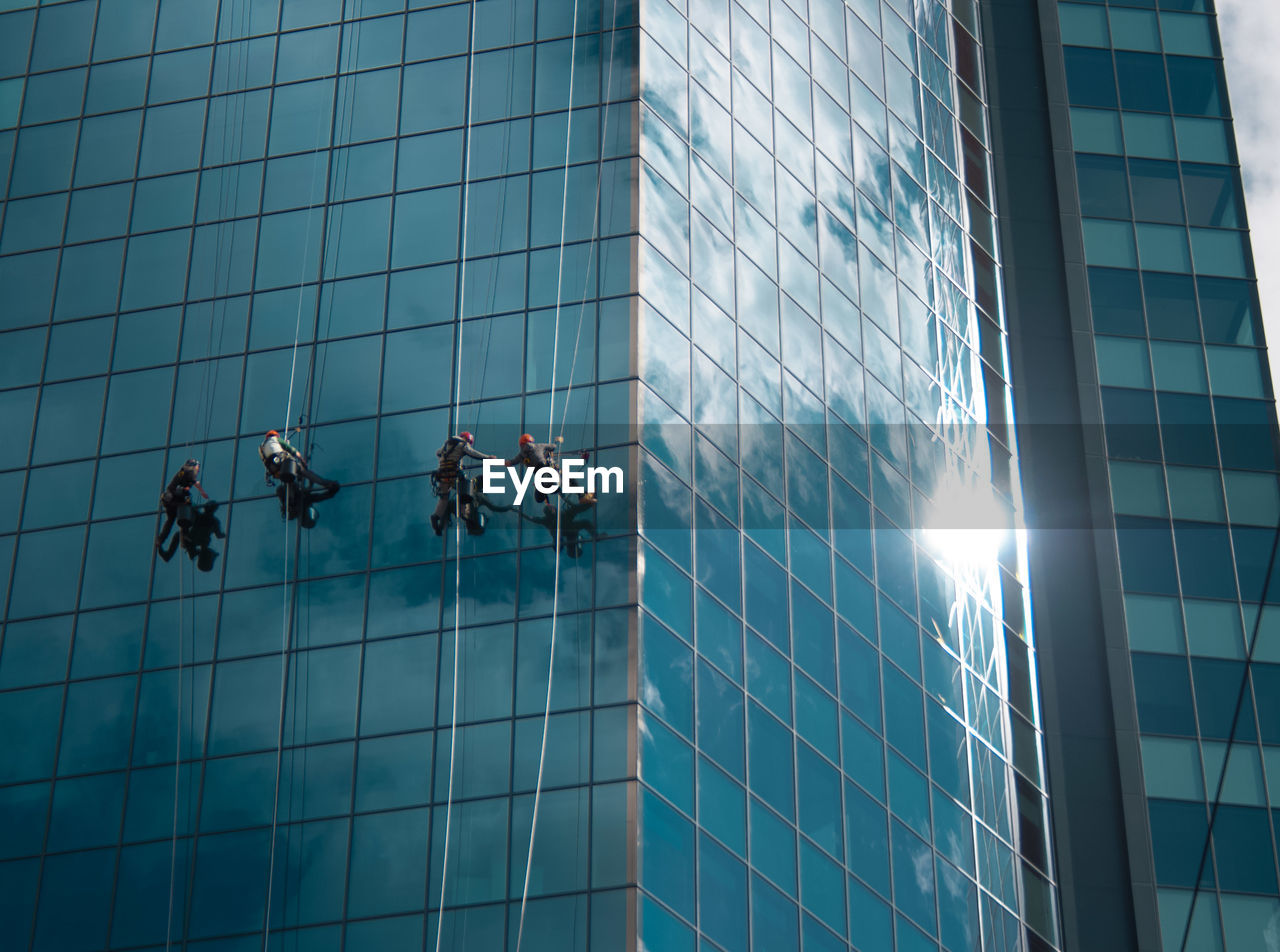 Low angle view of people cleaning modern glass building