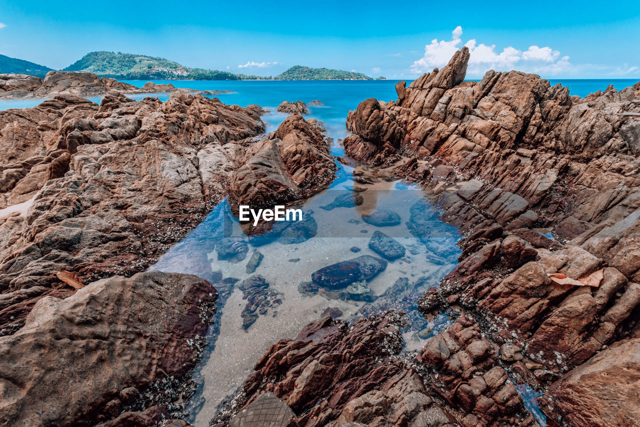 ROCK FORMATIONS ON SHORE AGAINST SKY