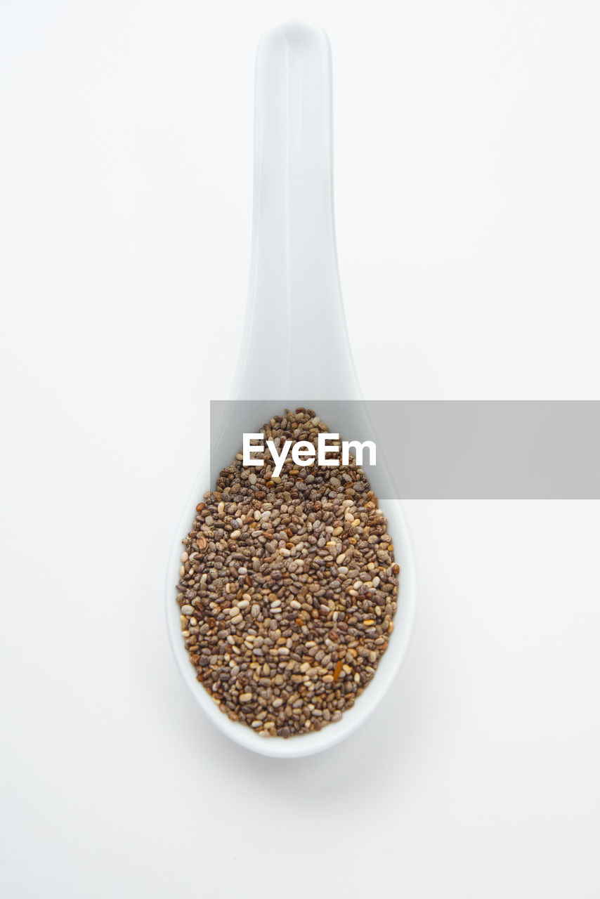 Close-up of chia seeds in spoon on white background