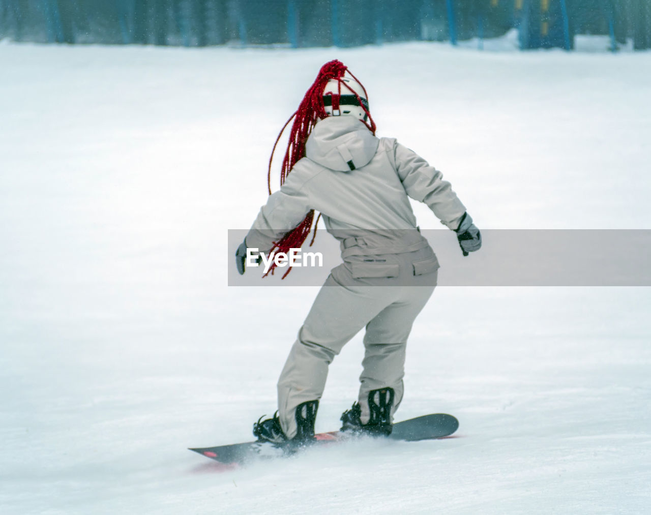 Snowboarder girl is riding a snowboard on the track.