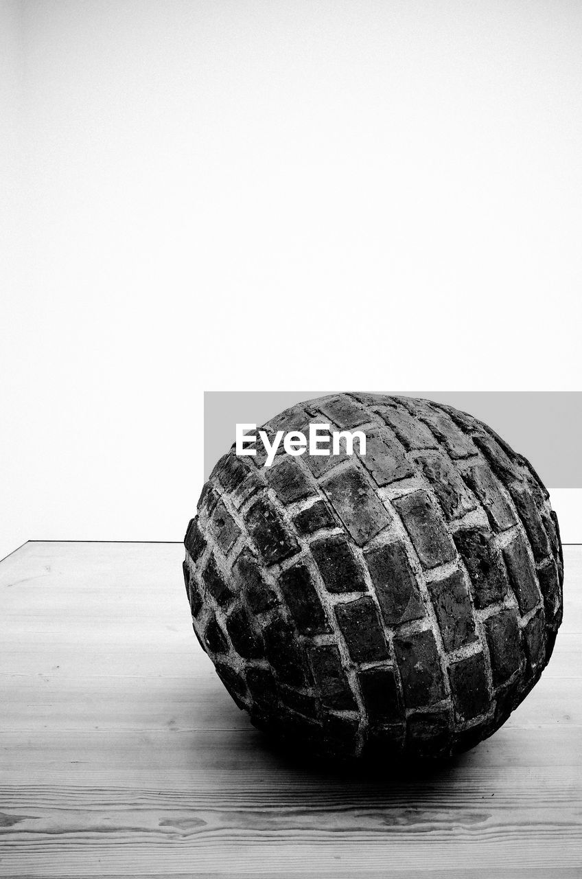 Close-up of brick ball on table against white background