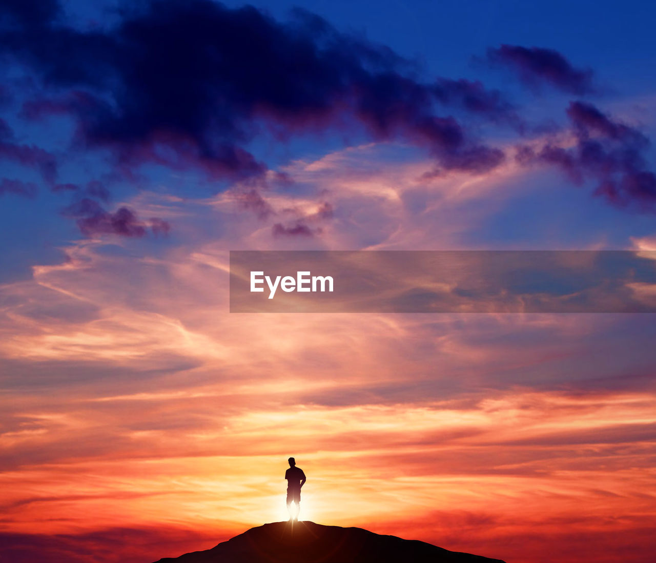 Silhouette man standing on mountain against cloudy sky during sunset