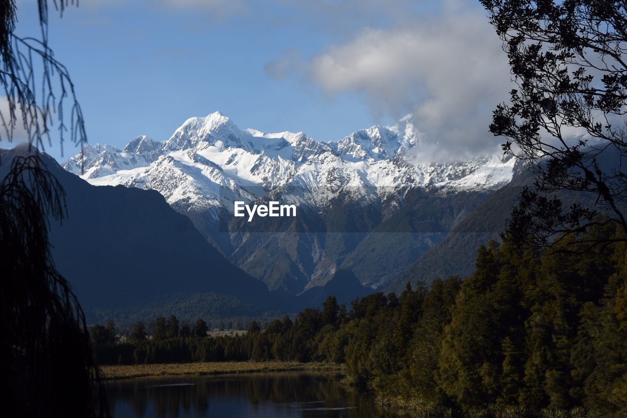 SCENIC VIEW OF MOUNTAINS AND TREES AGAINST SKY DURING WINTER