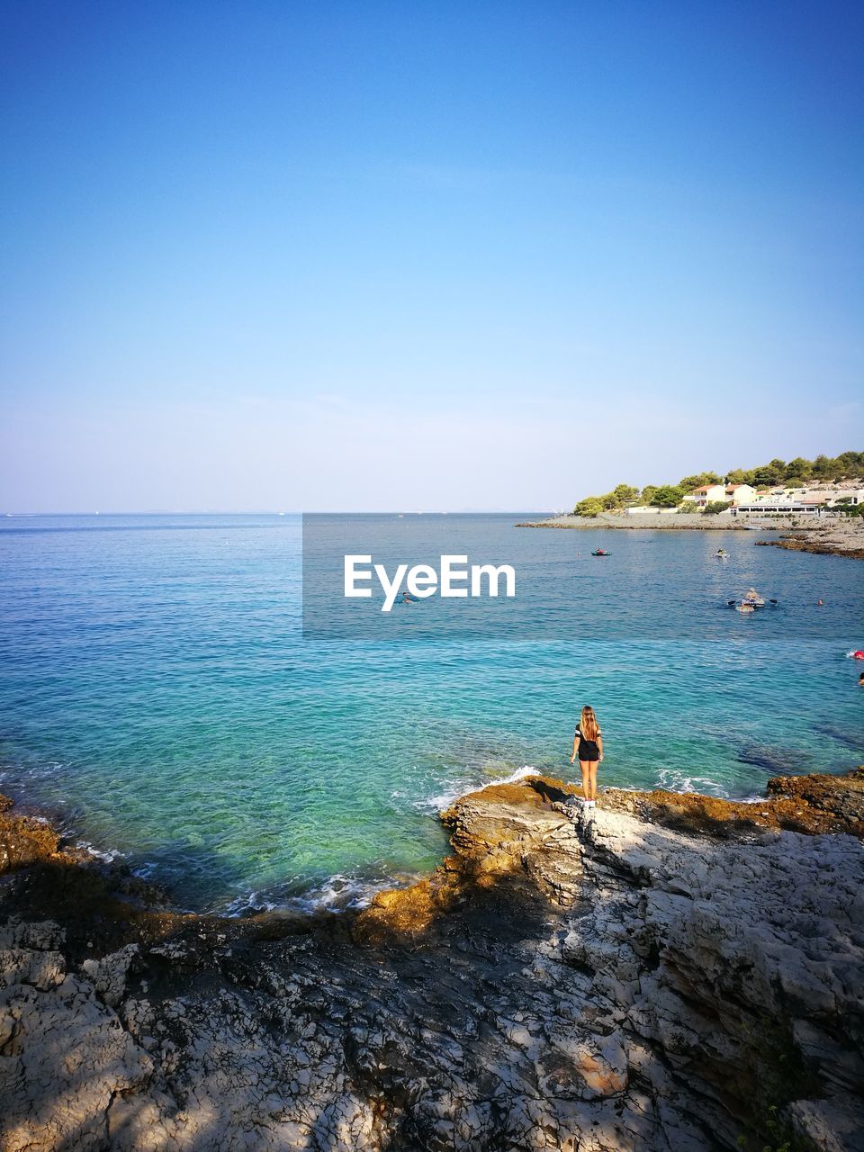 Scenic view of sea against clear blue sky with one person in view 