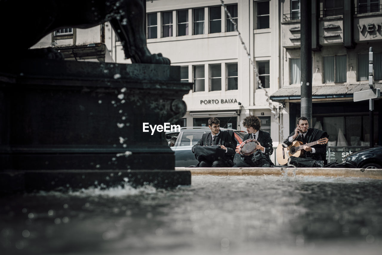 PEOPLE SITTING IN FRONT OF BUILDINGS