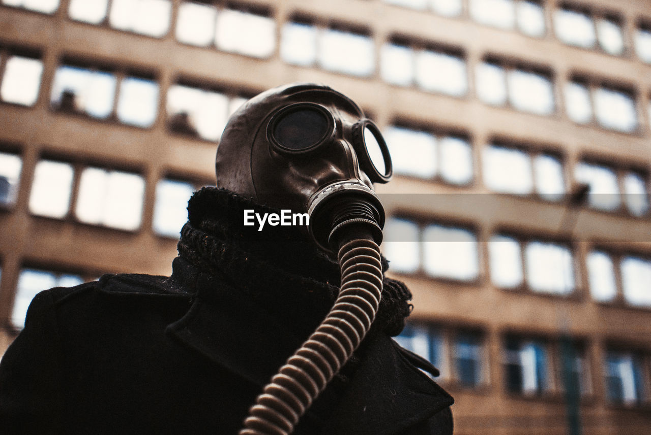 Low angle view of person wearing gas mask against building