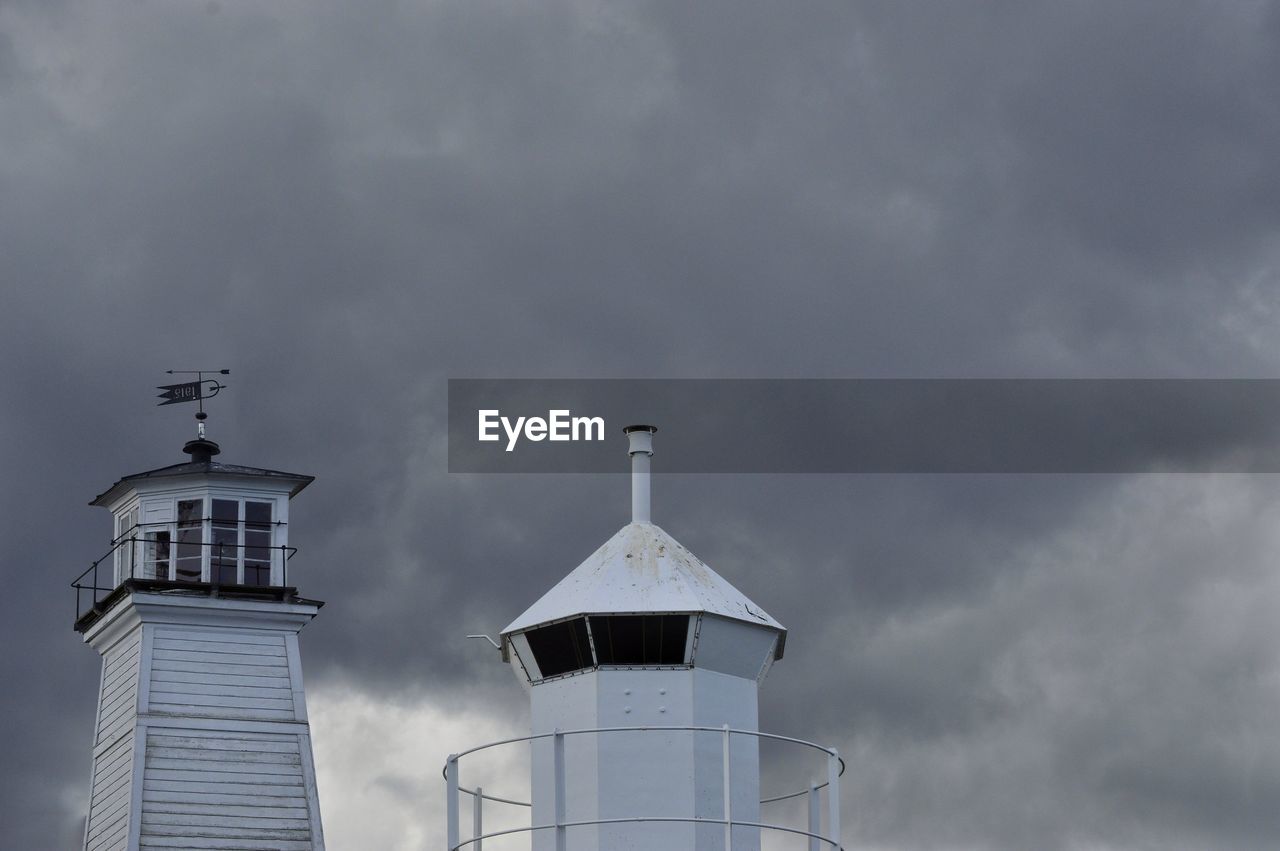 Low angle view of lighthouse by building against sky