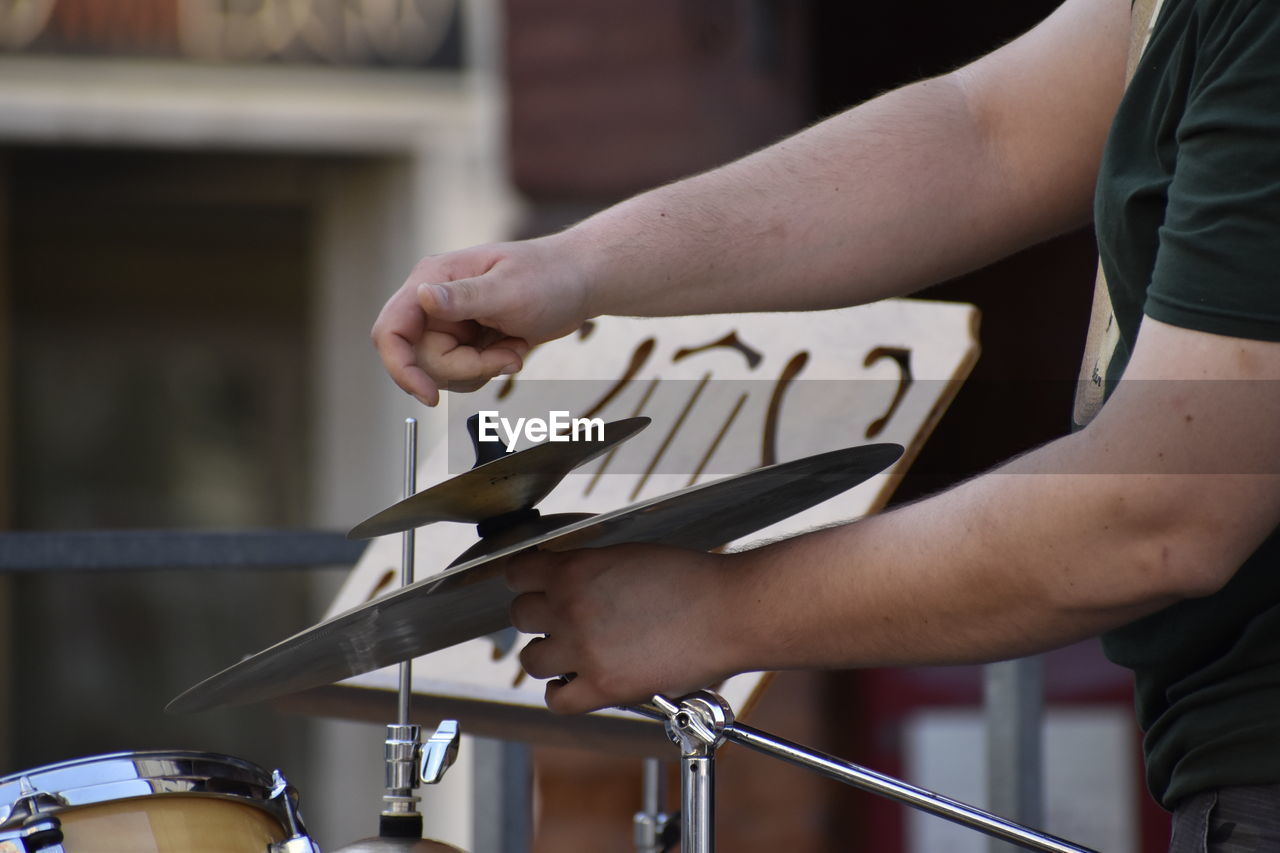 Midsection of man adjusting cymbal