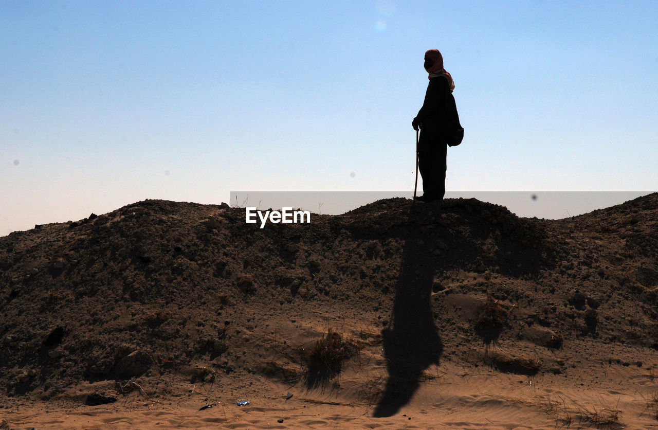 SILHOUETTE MAN STANDING ON ROCK AGAINST SKY