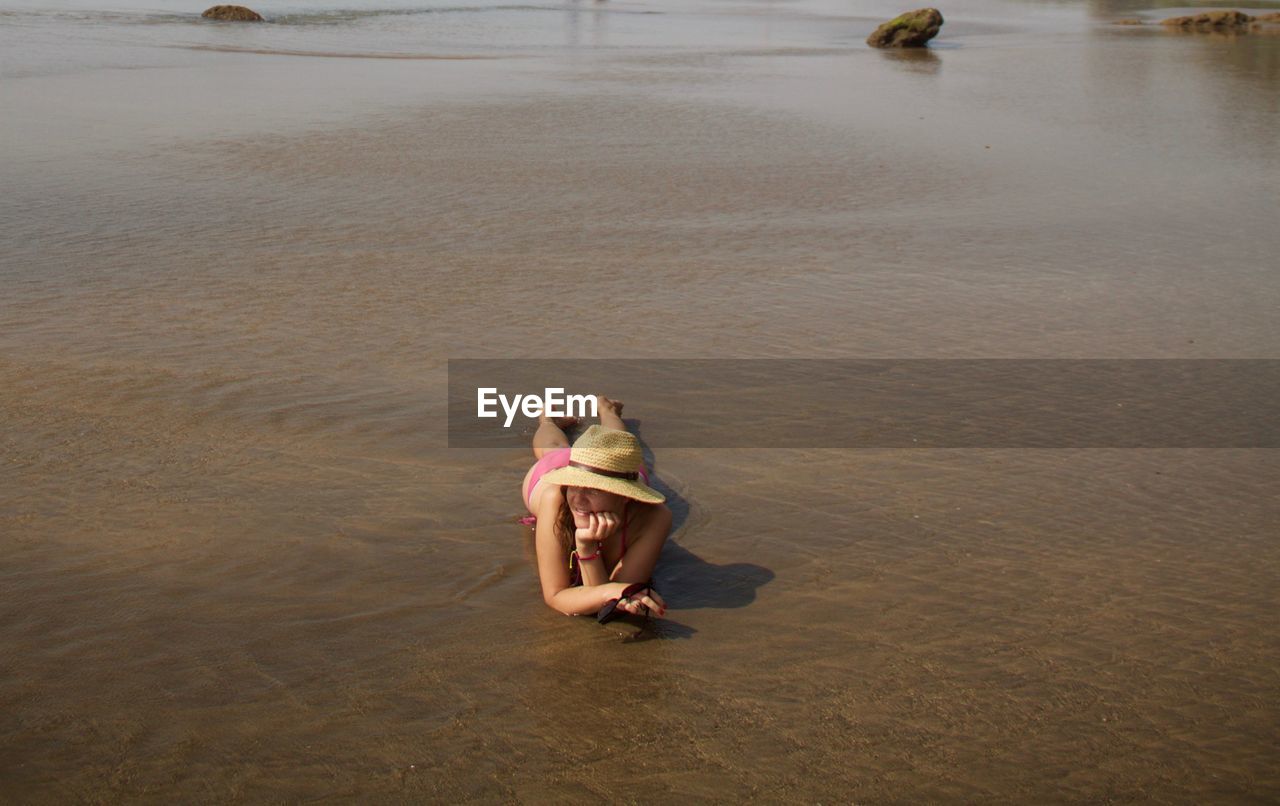 High angle view of woman lying on sand at beach