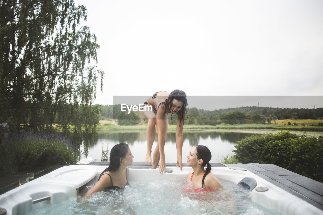 Female friends enjoying in hot tub during weekend getaway against clear sky