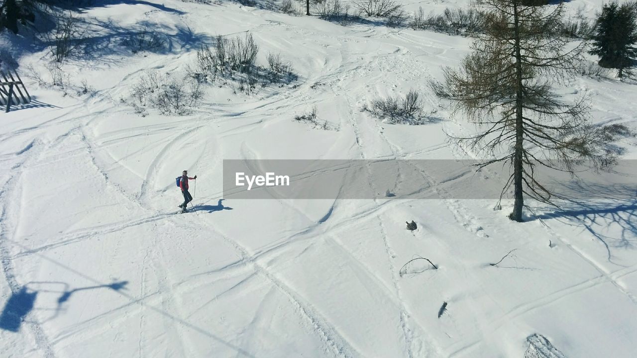 High angle view of man skiing on snowy field during sunny day