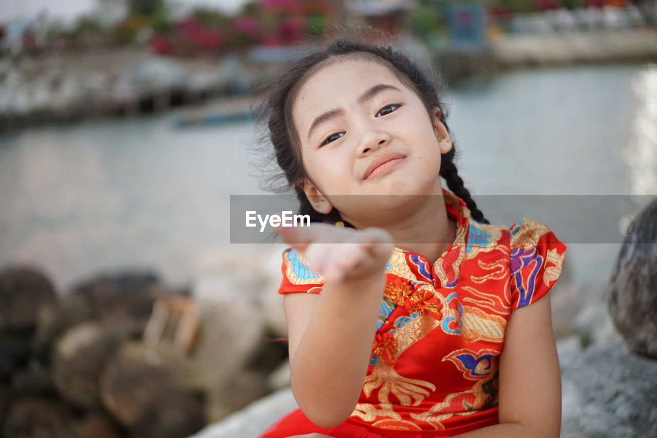 Portrait of smiling girl gesturing against sea