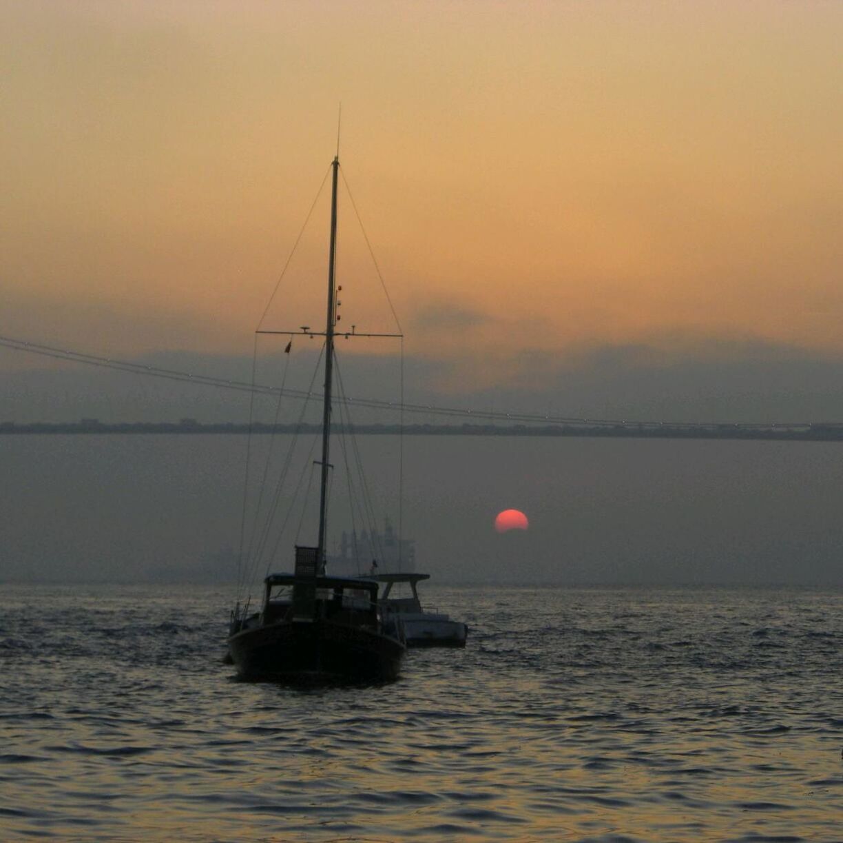 Scenic view of boat in sea against cloudy sky at sunset