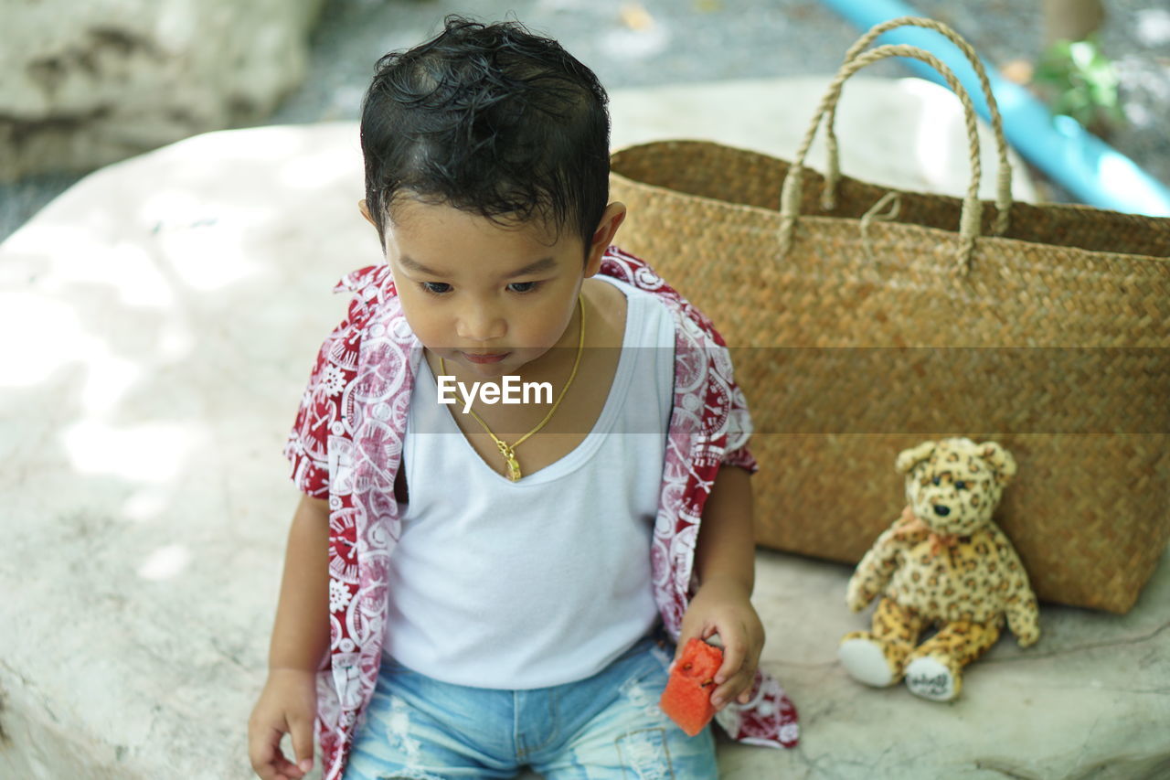 Cute baby boy eating fruit while sitting outdoor