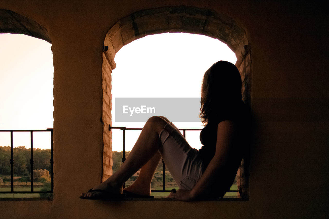 Woman sitting under arch 