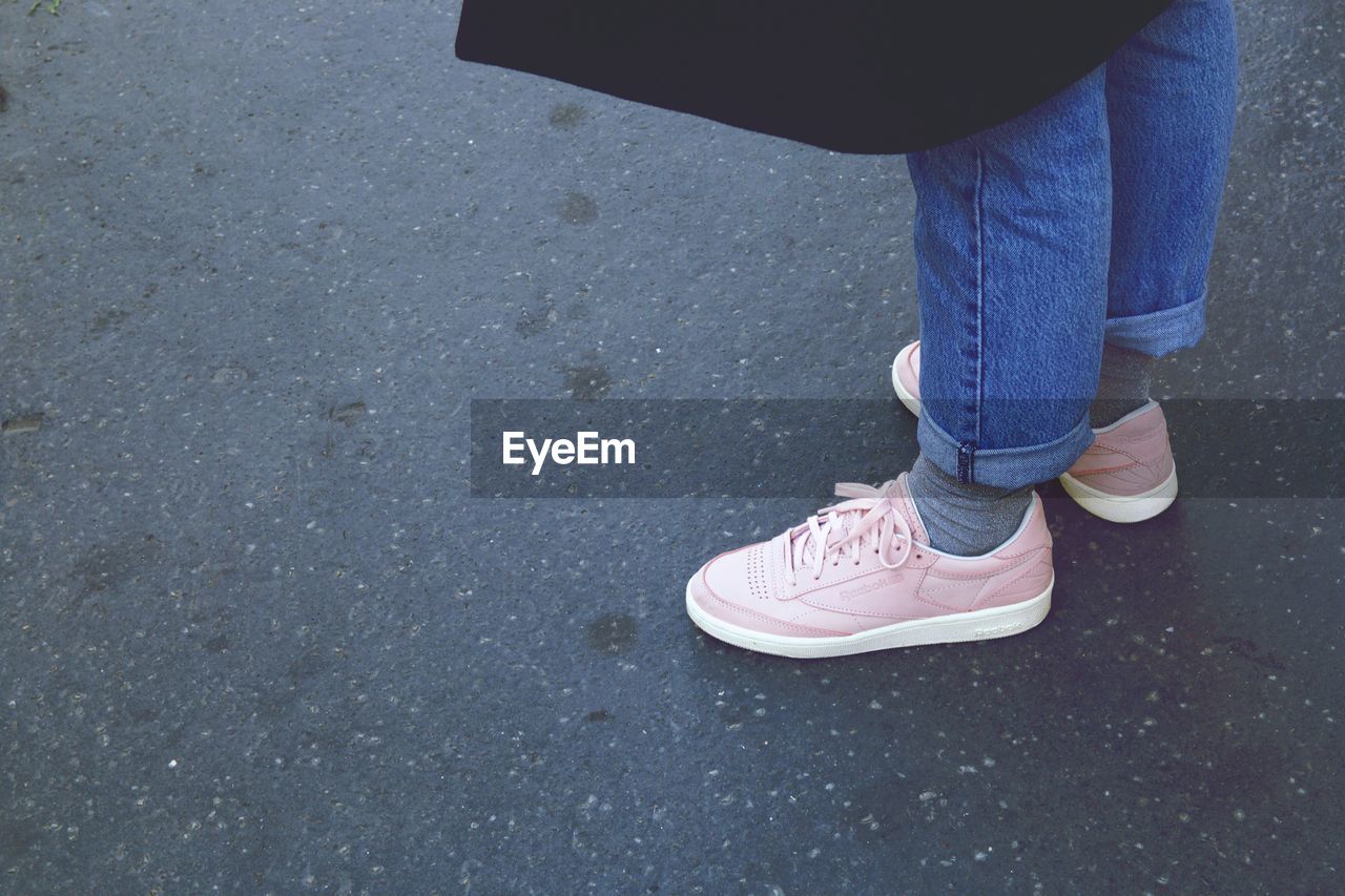 Low section of woman wearing pink shoes on road