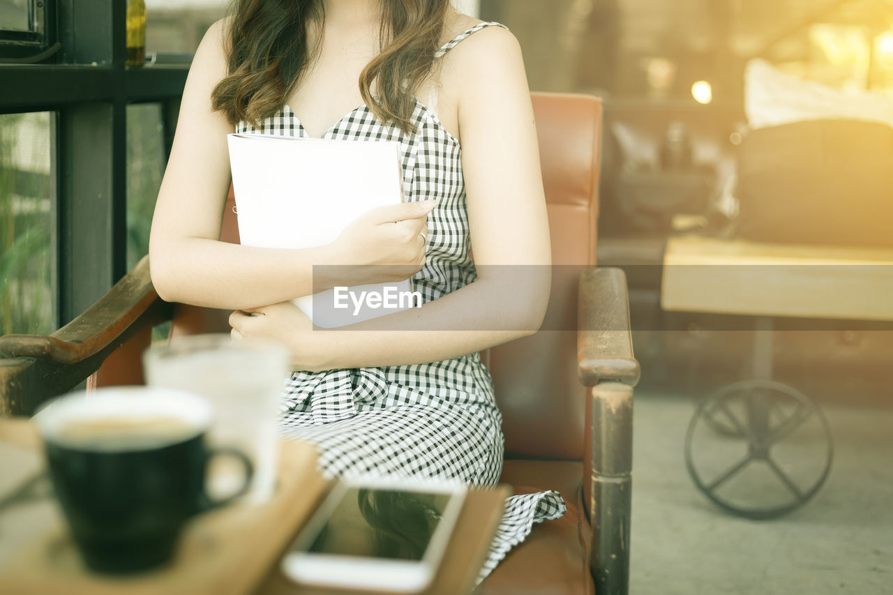 WOMAN SITTING ON TABLE IN CAFE