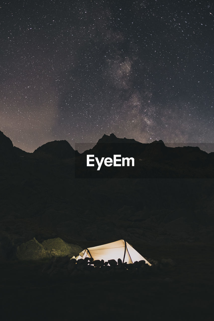 Tent at night agains the milky way over the mountains sierra de gredos