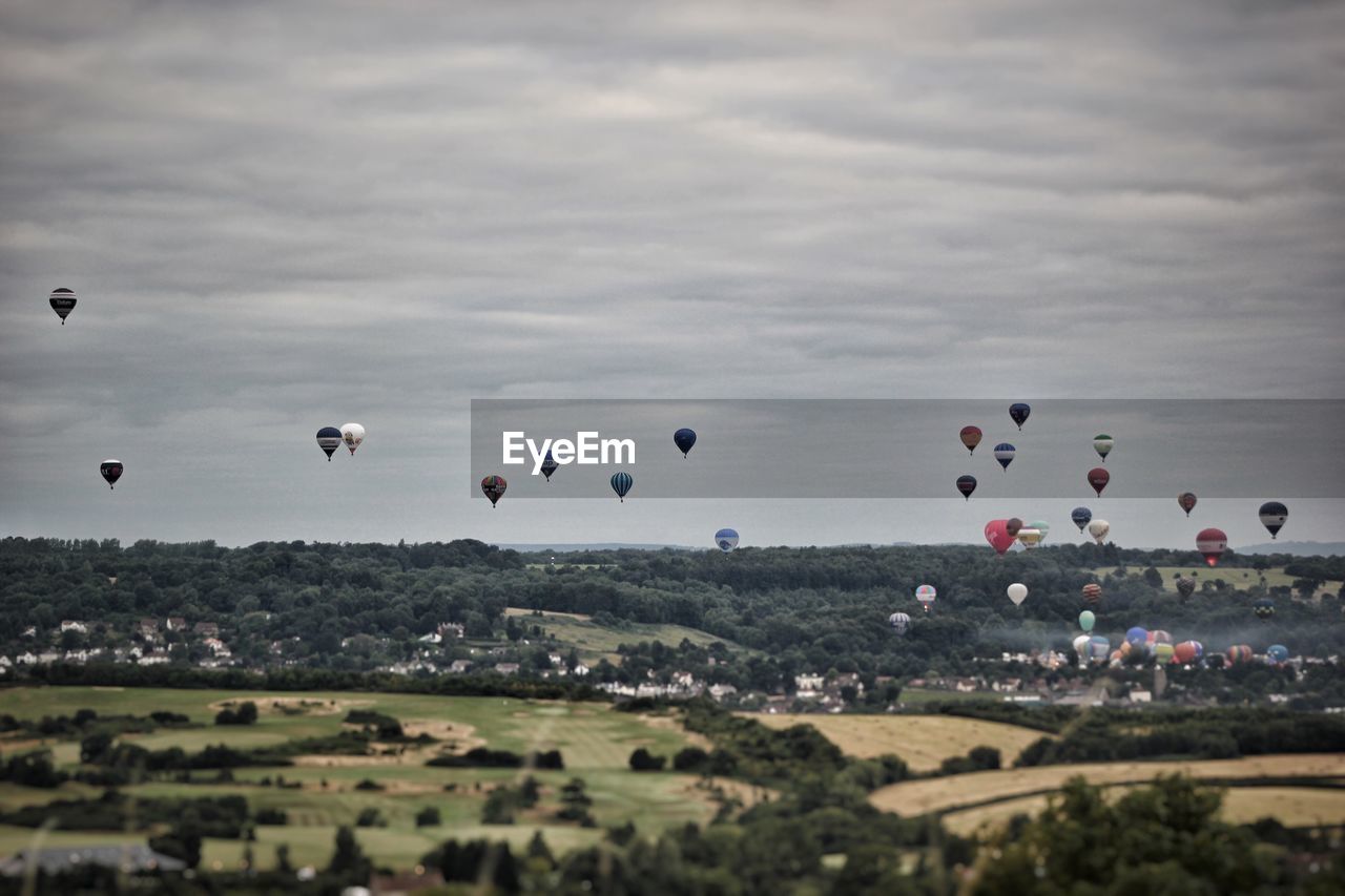 Hot air balloons flying in the bristol balloon fiesta against cloudy sky