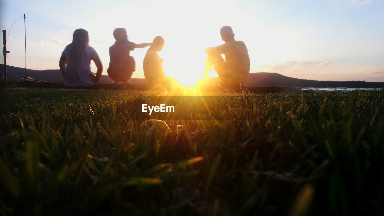 People sitting on grass in park against sky