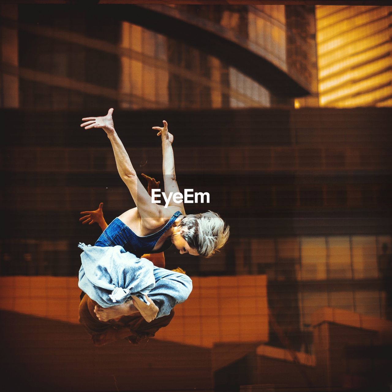 Full length of young woman jumping against buildings