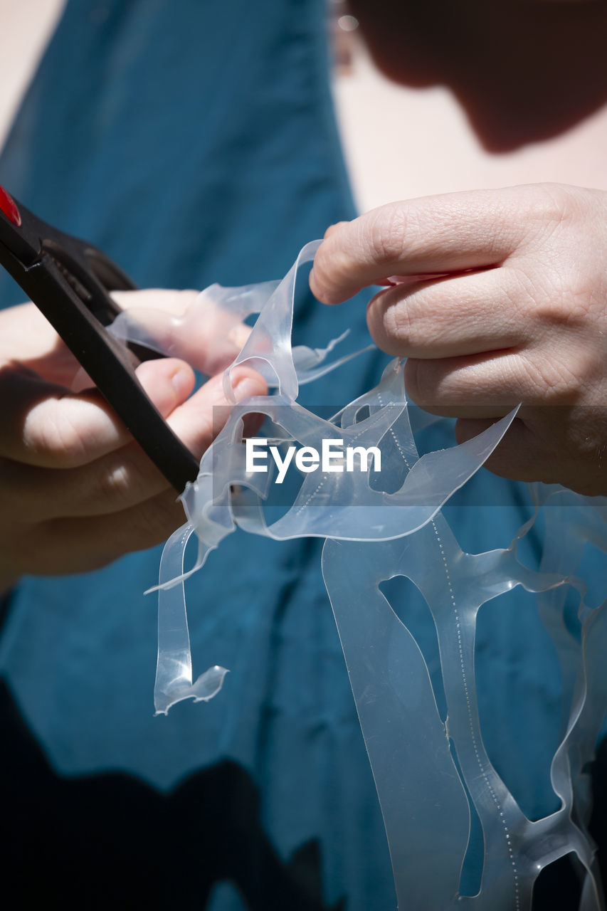 Midsection of woman cutting plastic with scissors