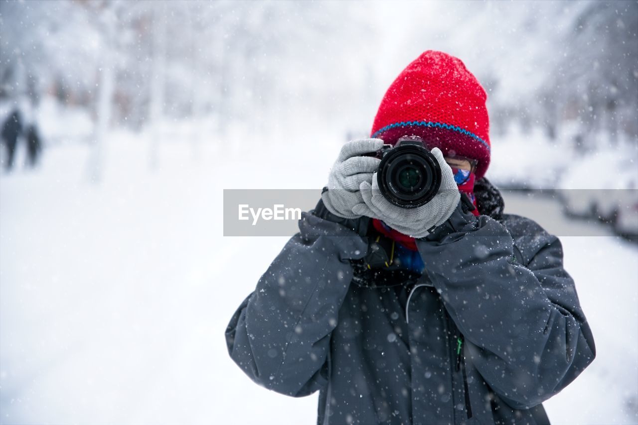 A teenage girl takes photos during the snowfall