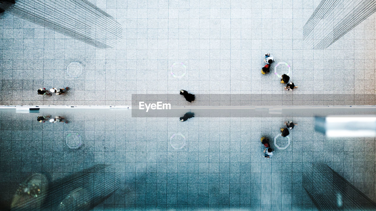 Directly above shot of people walking on street by glass building