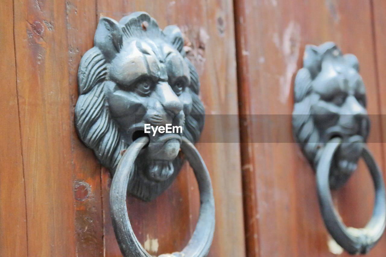 CLOSE-UP OF DOOR KNOCKER ON WOOD AGAINST WOODEN WALL