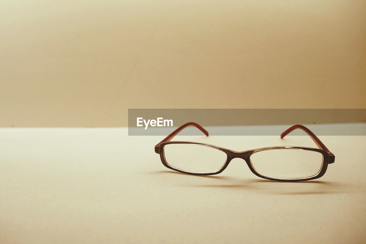 Close-up of eyeglasses on table against wall