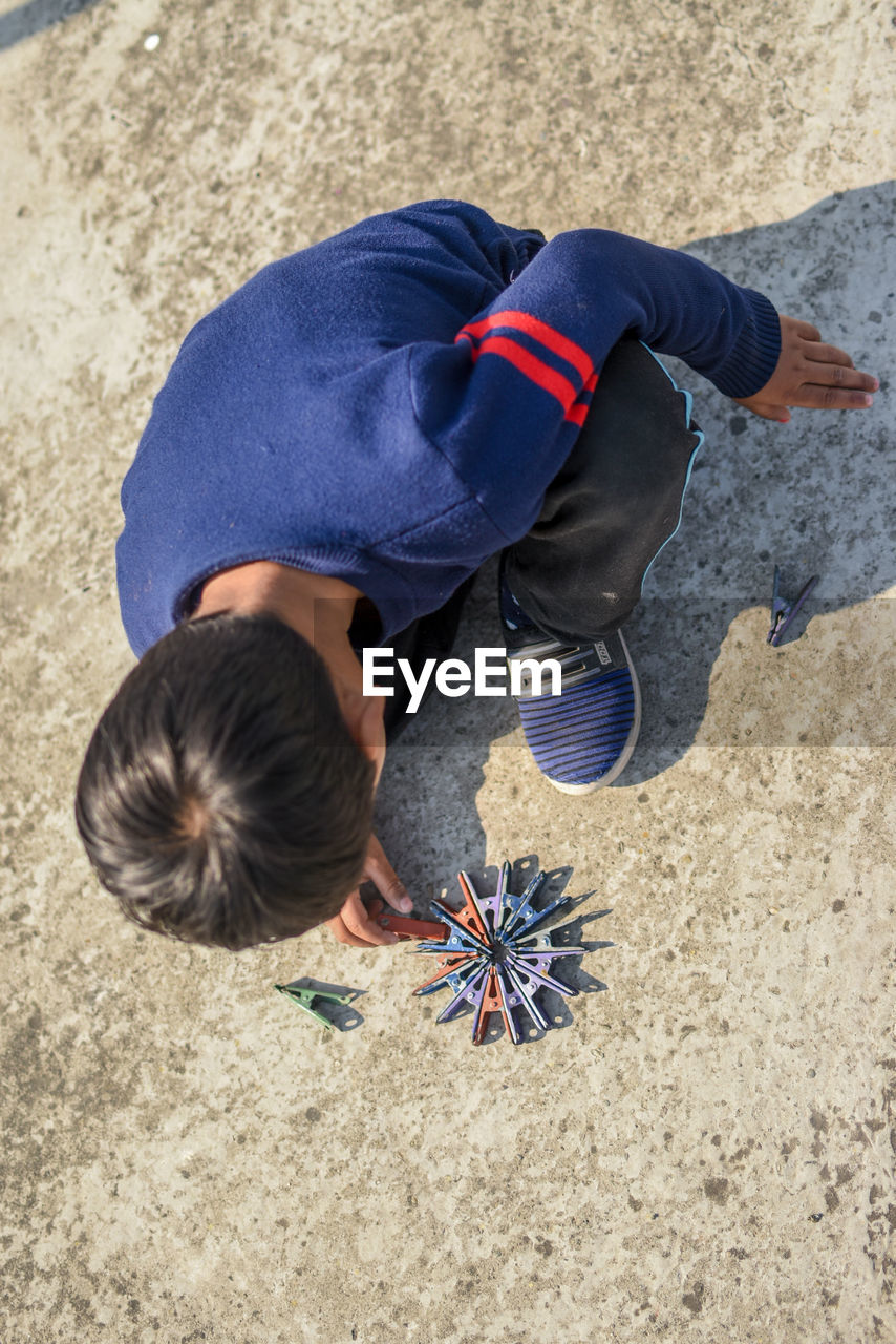 HIGH ANGLE VIEW OF BOY PLAYING WITH SAND