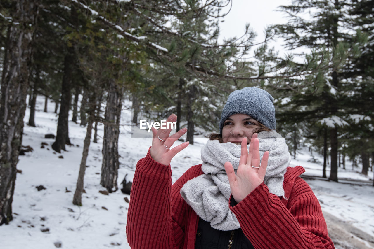 Portrait of young woman standing on snow covered field