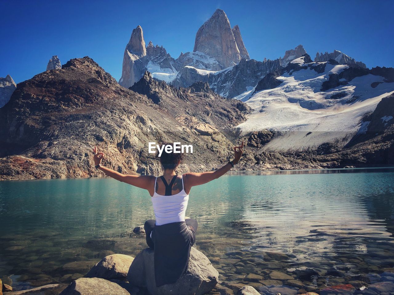 Rear view of person on rock in water against sky