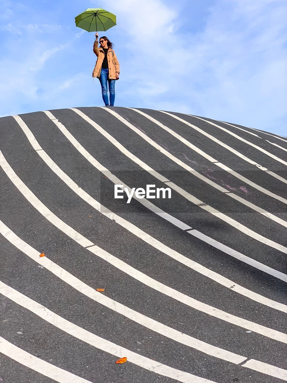 Low angle view of woman with umbrella standing on road 