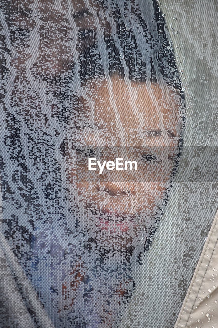 Boy seen through wet netting